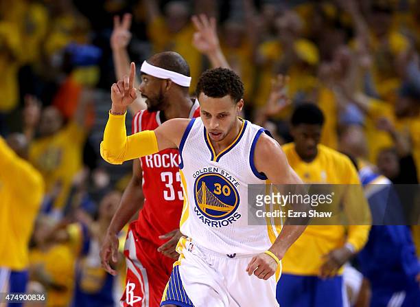 Stephen Curry of the Golden State Warriors reacts in front of Corey Brewer of the Houston Rockets after making a three-pointer in the first half...