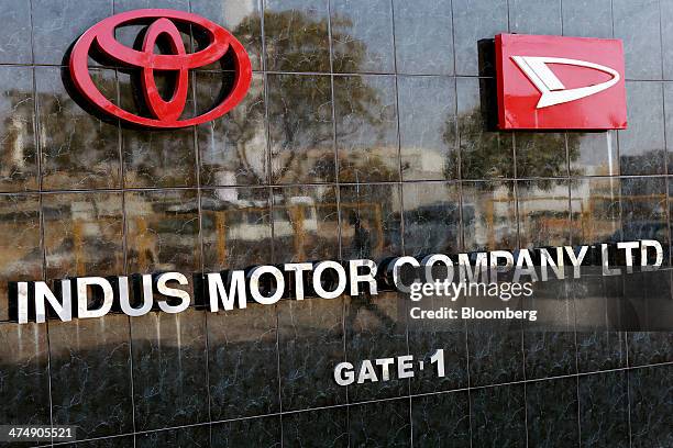 Signage for Indus Motor Co., the Pakistan affiliate of Toyota Motor Corp., and the logos of Toyota and Daihatsu Motor Co. Are displayed on an...
