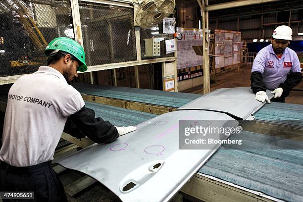 Employees of Indus Motor Co., the Pakistan affiliate of Toyota Motor Corp., inspect pressed metal door panels for Toyota Corolla vehicles at the...