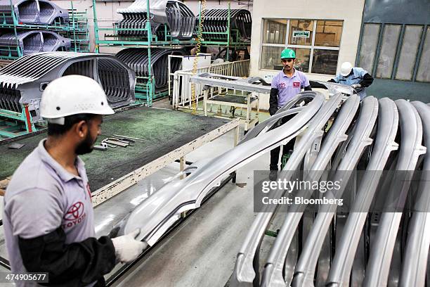 Employees of Indus Motor Co., the Pakistan affiliate of Toyota Motor Corp., move a pressed metal door frame for a Toyota Corolla vehicle at the...