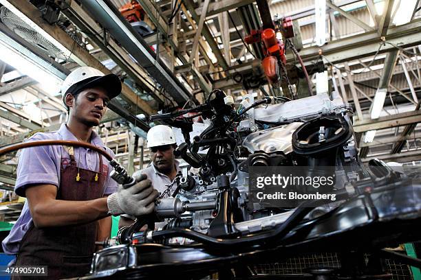Employees of Indus Motor Co., the Pakistan affiliate of Toyota Motor Corp., assemble an engine for a Toyota Corolla vehicle at the company's plant in...
