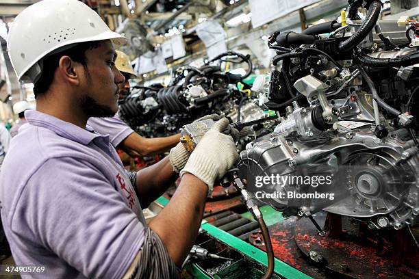 An employee of Indus Motor Co., the Pakistan affiliate of Toyota Motor Corp., assembles an engine for a Toyota Corolla vehicle at the company's plant...