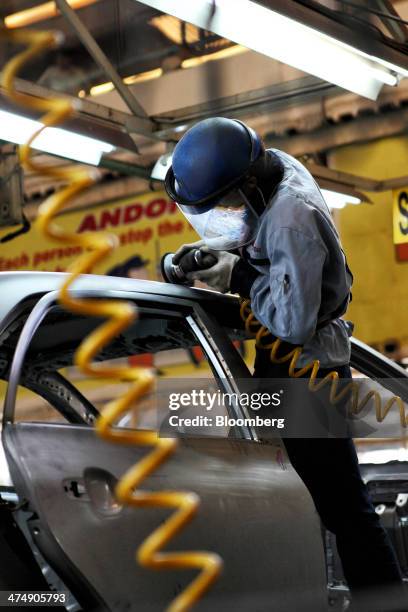 An employee of Indus Motor Co., the Pakistan affiliate of Toyota Motor Corp., grinds the body of a Toyota Corolla vehicle at the company's plant in...