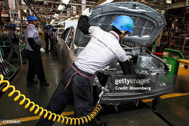 Employees of Indus Motor Co., the Pakistan affiliate of Toyota Motor Corp., work on the Toyota Corolla assembly line of the company's plant in...