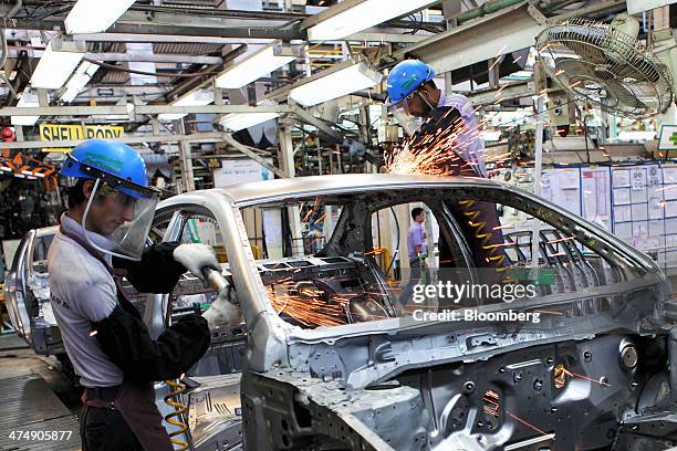 Employees of Indus Motor Co., the Pakistan affiliate of Toyota Motor Corp., grind the body of a Toyota Corolla vehicle at the company's plant in...