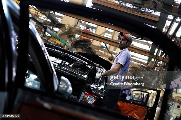 An employee of Indus Motor Co., the Pakistan affiliate of Toyota Motor Corp., makes a final inspection of a Toyota Corolla GLi automobile assembled...