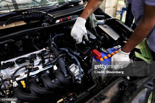An employee of Indus Motor Co., the Pakistan affiliate of Toyota Motor Corp., fits the battery of a Toyota Corolla GLi automobile on the assembly...