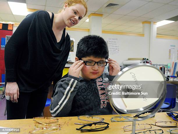 Ellen Marcus, research assistant and a student at Johns Hopkins University, second-grader Anthony Martinez try on eyeglass frames. Dr. Megan Collins...