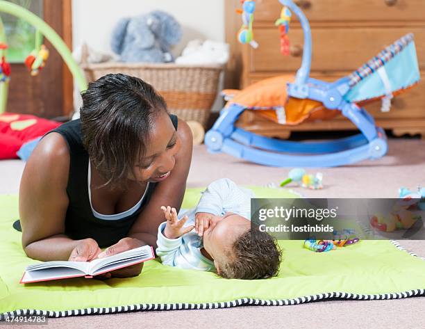 storytime on the playmat with carer and baby - nanny stock pictures, royalty-free photos & images