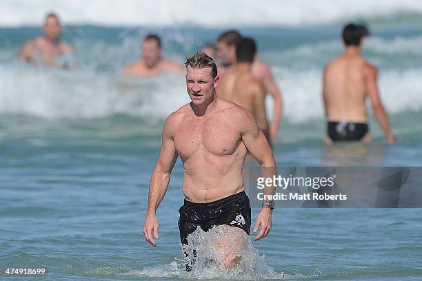 Magpies coach Nathan Buckley walks out of the water during a Collingwood Magpies AFL beach session at the Southport Spit on February 26, 2014 on the...
