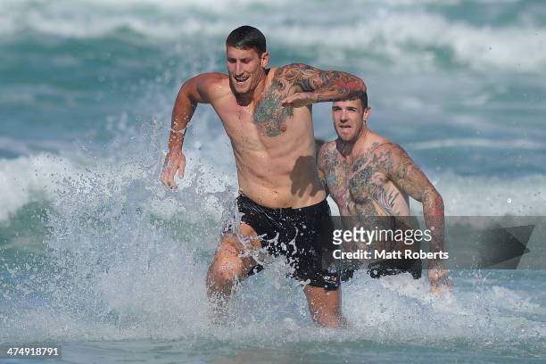 Jesse White runs out of the water ahead of Dane Swan during a Collingwood Magpies AFL beach session at the Southport Spit on February 26, 2014 on the...