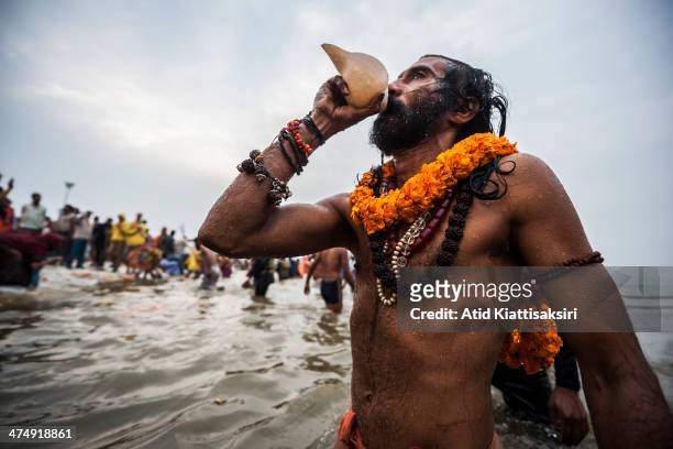 Naga sadhu blows a conch shell while bathing in the Ganges river during the Shahi Snan of Basant Panchami, the main bathing day of Maha Kumbh Mela.