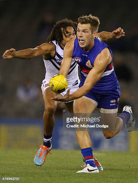 Shaun Higgins of the Bulldogs handpasses the ball away from Tendai Mzungu of the Dockers during the round three AFL NAB Challenge match between the...