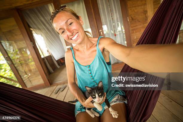 fröhlich frau in hängematte mit kitty schülern - cat selfie stock-fotos und bilder