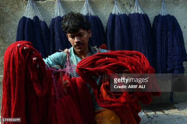 Pakistani labourer prepares dyed wool to make carpets at a factory in Lahore on February 26, 2014. Pakistan was on track to receive a third loan...