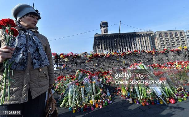 Woman holds flowers near a memorial for protesters who were victims of recent clashes with police, at Independence Square in Kiev on February 26,...