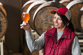 Worker in a microbrewery inspecting glass of beer