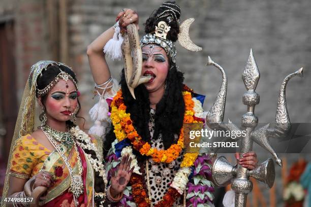 Indian Hindu devotees dressed as Hindu god Lord Shiva , seen holding a snake to his mouth, and Mata Parvati participate in a procession on the eve of...