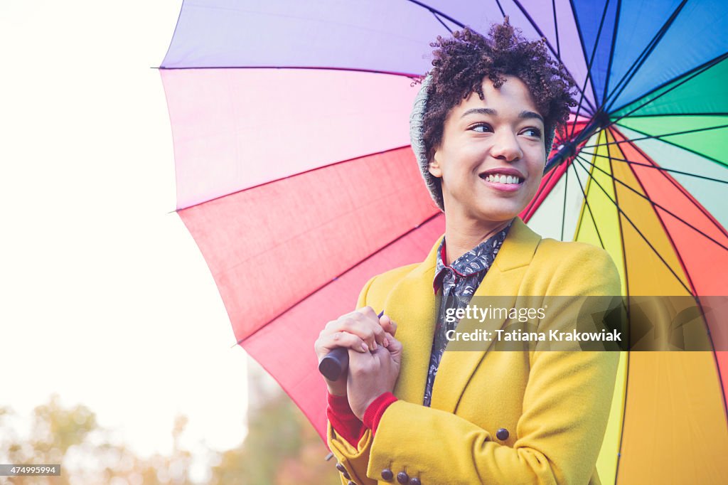 Smiling woman under colorful umbrella (London, UK)