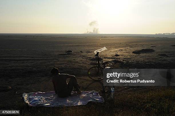 Lapindo mudflow victim sits near mudflow area watching the sunrise on May 29, 2015 in Porong, Indonesia. Lapindo mudflow eruption is suspected to...