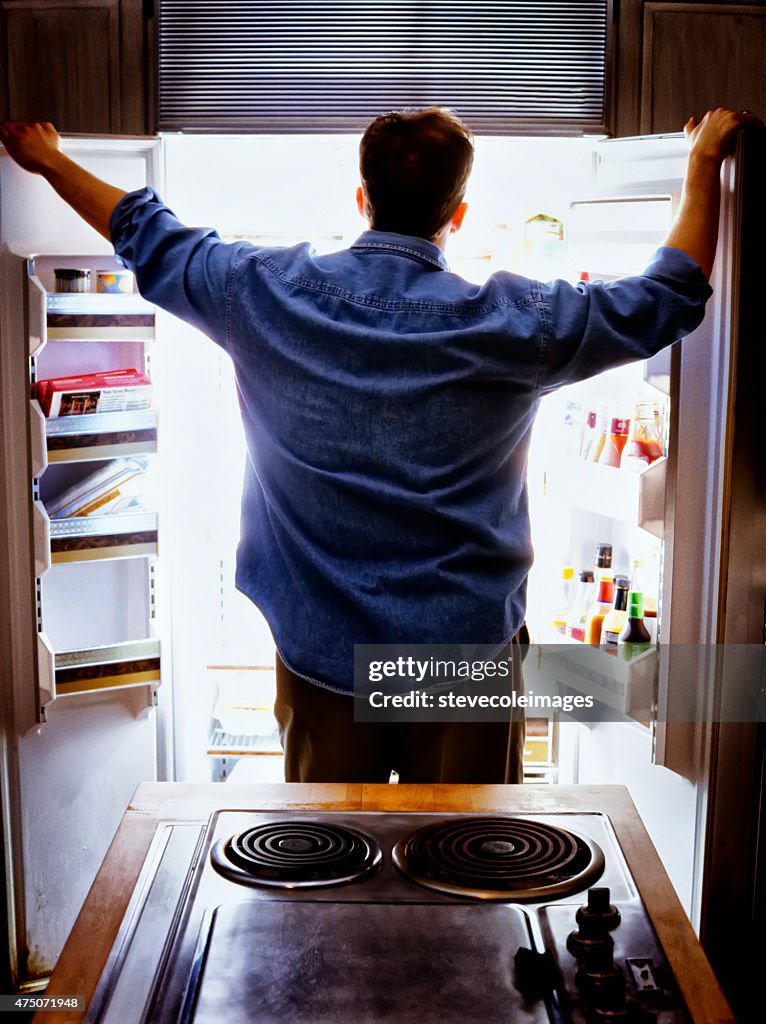 Hombre mirando a un refrigerador para alimentos.