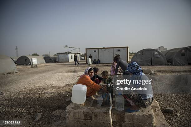 Syrian women and girls fill the buckets with water in Suruc district of Sanliurfa, Turkey on May 28, 2015. Syrian refugees fled their home due to the...