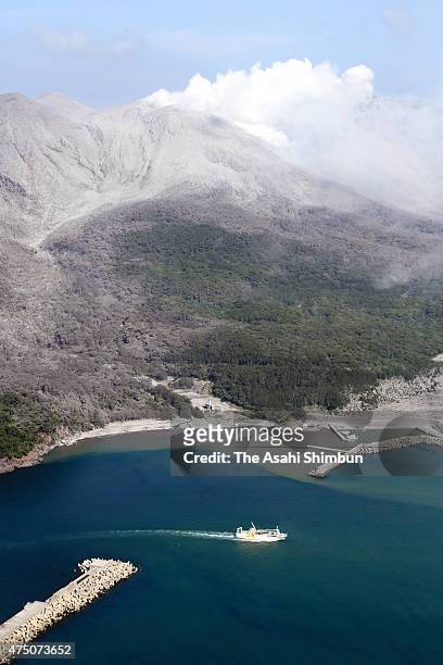 In this aerial image, volcanic ash spews while a ferry carring evacuating residents leaves the Kuchinoerabu Island for Yakushima Island on May 29,...