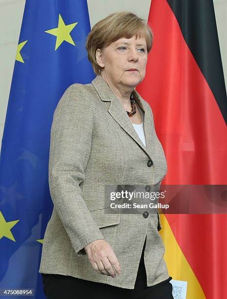 German Chancellor Angela Merkel walks past the flags of the European Union and Germany as she arrives to speak to the media with British Prime...