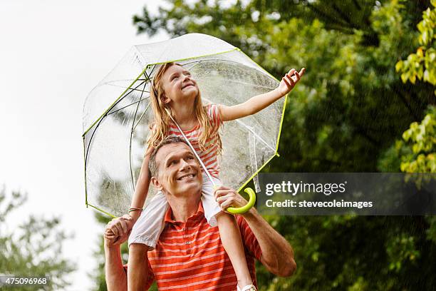 father and daughter in the rain. - family in rain stockfoto's en -beelden