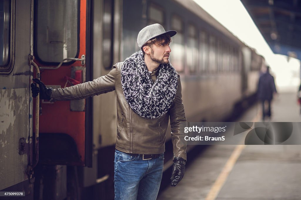 Young man leaving the train at railroad station.