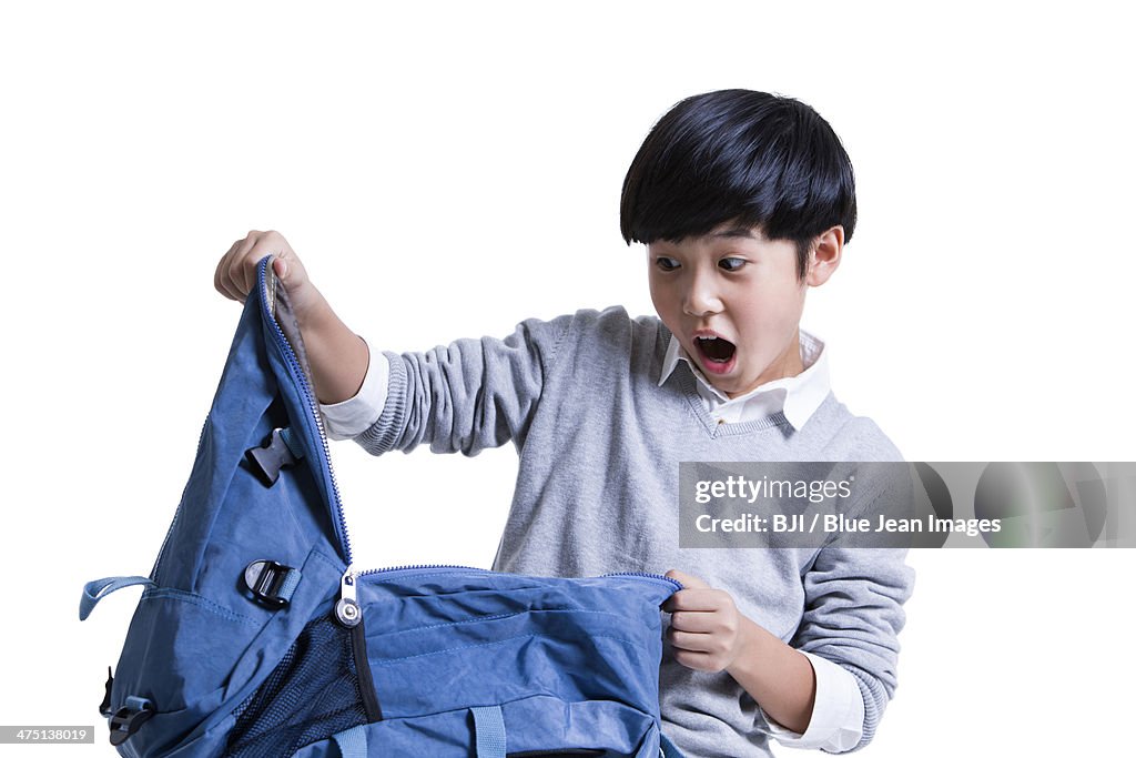 Cute schoolboy opening book bag with surprise