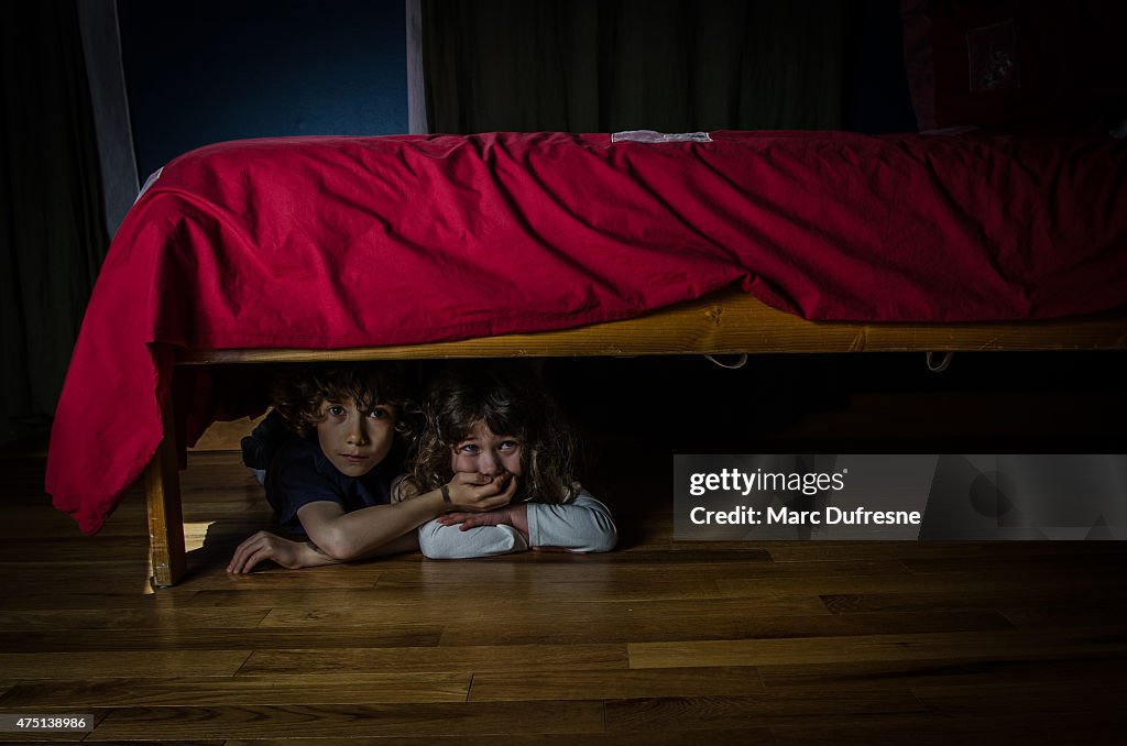 Kids hidden under the bed with fear and crying