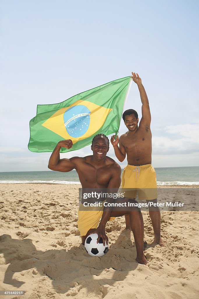 Men posing with brazilian flag on beach