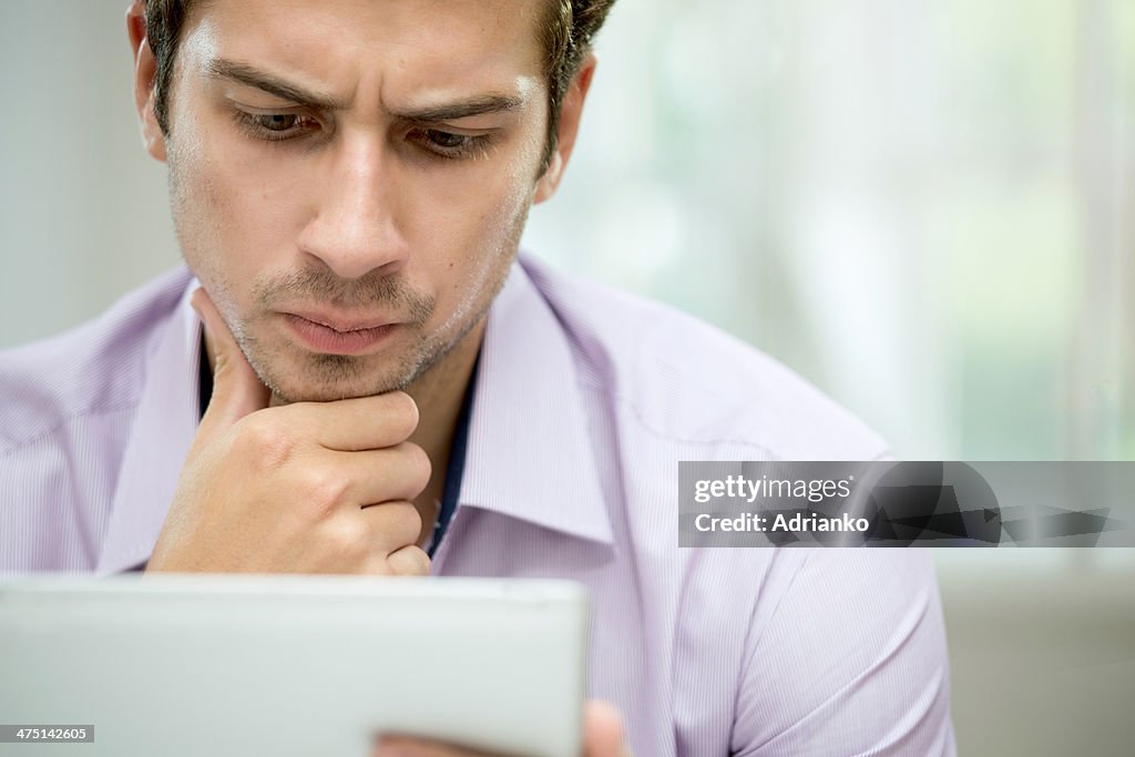 Young man looking at message on digital tablet