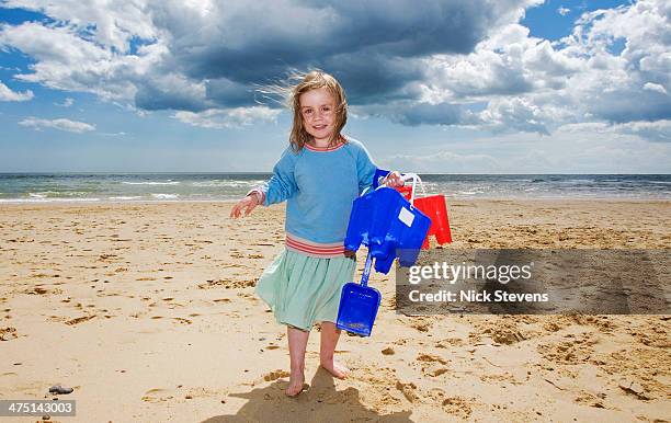 young girl holding bucket and spade on beach, walberswick, suffolk, england, uk - walberswick stock pictures, royalty-free photos & images