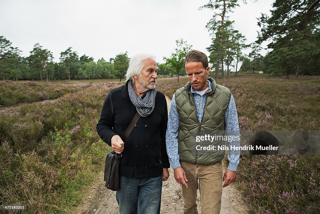 Father and adult son walking on dirt track