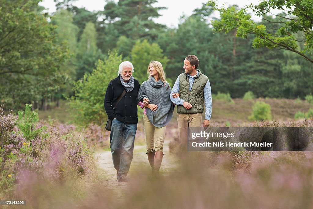 Senior man, mid adult man and woman walking through forest