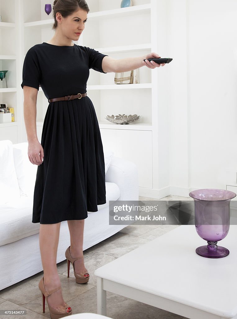 Young woman wearing black dress using remote control