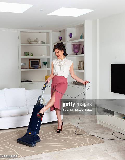 young woman using vacuum cleaner in living room - housewife stock pictures, royalty-free photos & images