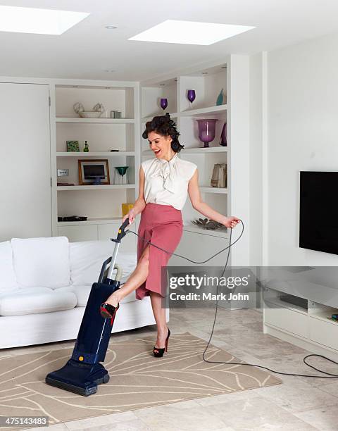 young woman using vacuum cleaner in living room - 1950 females only housewife stock pictures, royalty-free photos & images