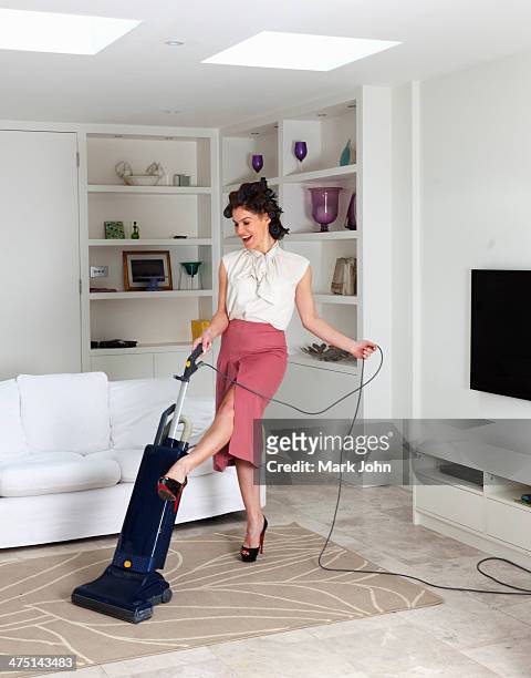young woman using vacuum cleaner in living room - homemaker - fotografias e filmes do acervo