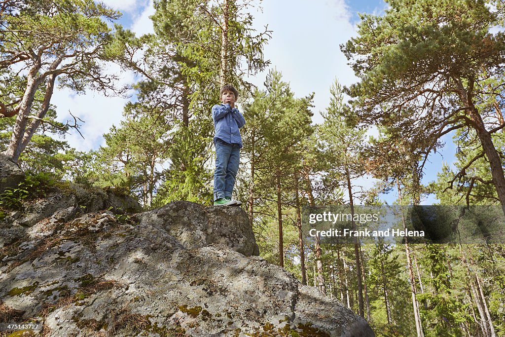 Boy standing on top of rock