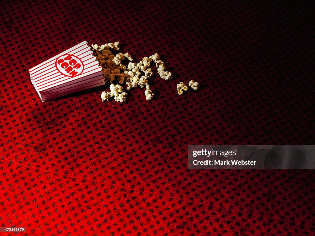 Spilled carton of popcorn on cinema carpet