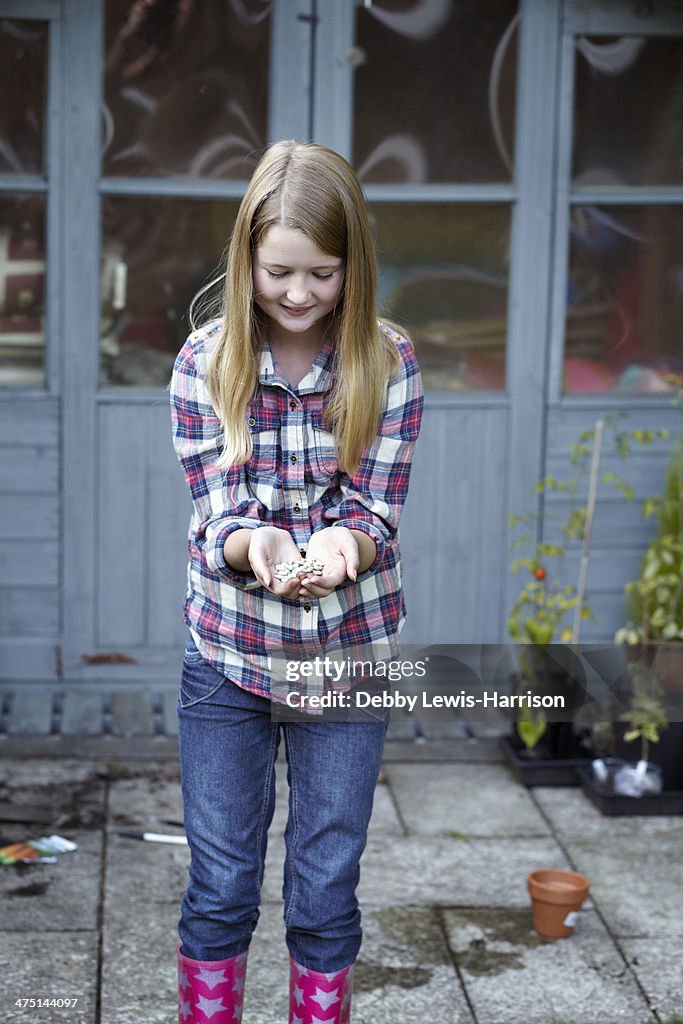 Girl in garden cupping seeds in hand