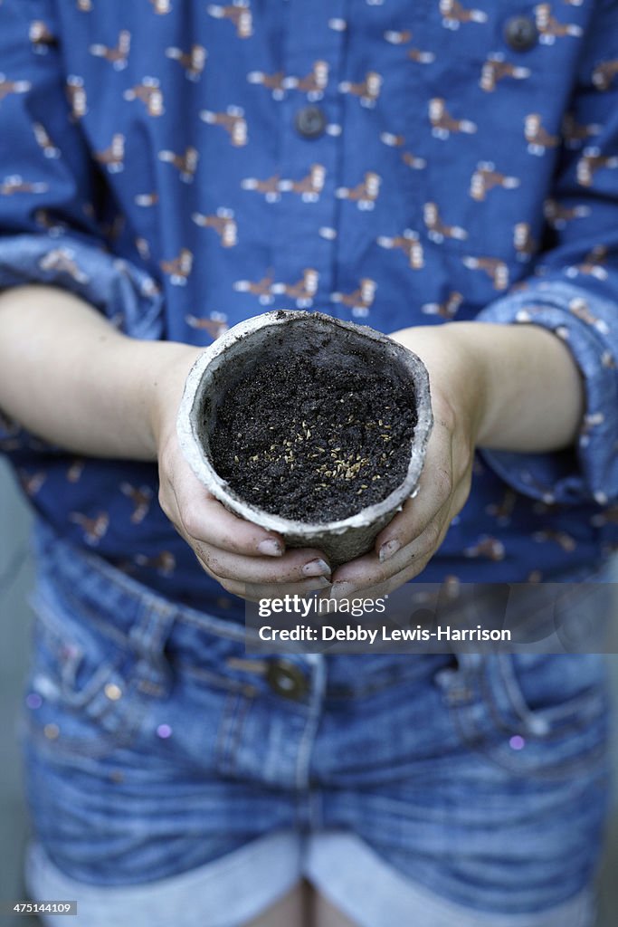 Close up of girl holding flower pot with seeds