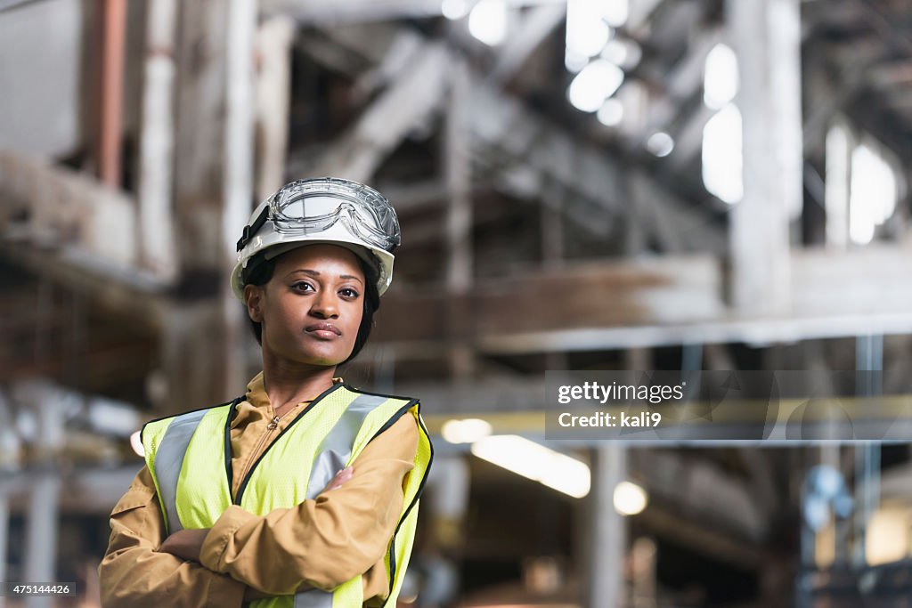 Afrikanische amerikanische Frau mit Bauarbeiterhelm und Sicherheit Weste