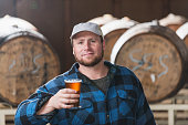Worker in a microbrewery holding glass of beer