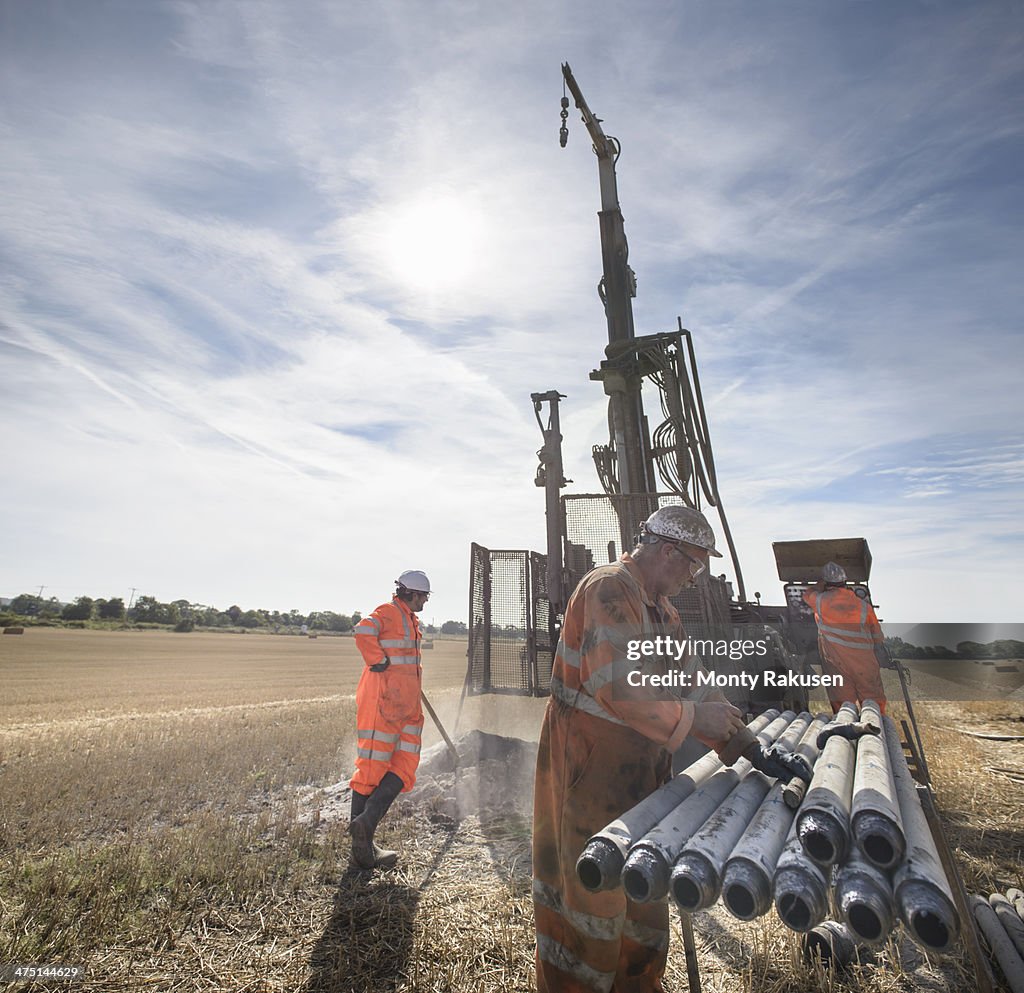 Workers operating drilling rig in field