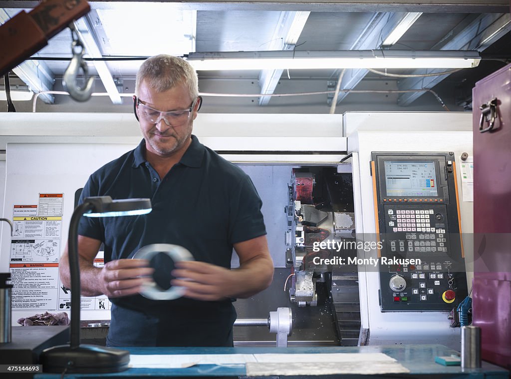 Engineer inspecting metal part in factory