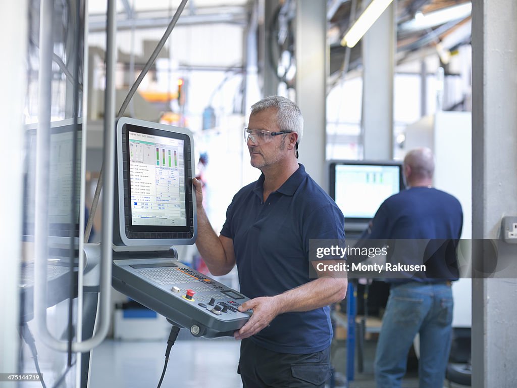 Engineers at lathe controls in factory